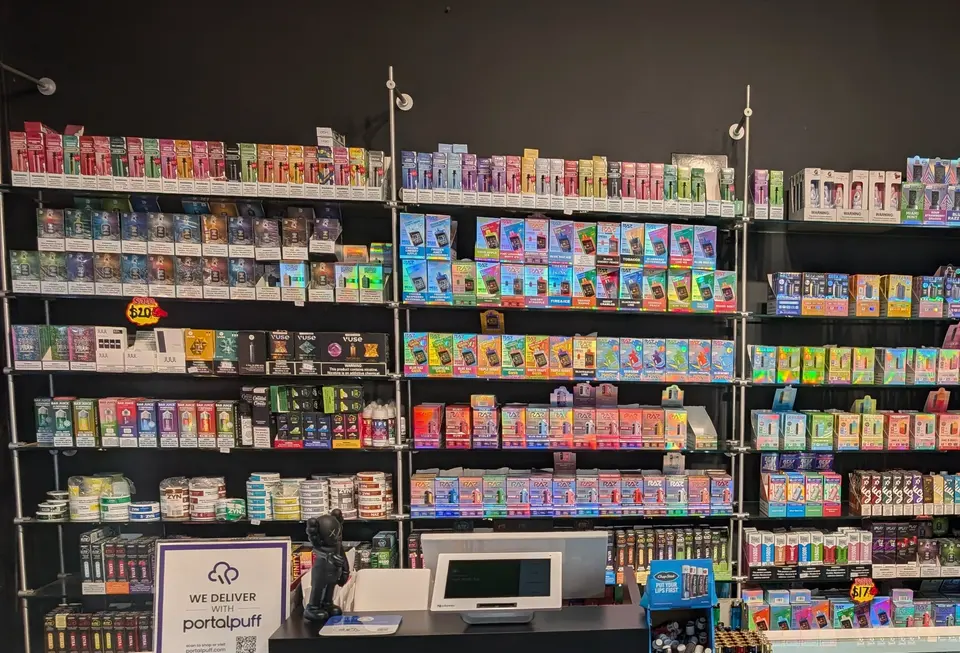Shelves of disposable vapes, pods and e-liquid at Fancy Puffs, with RAZ, Geek Bar, HQD, JUUL and Vuse packaging on the racks.